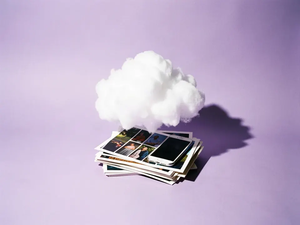 Una nube de algodón flotando sobre fotos impresas y un teléfono