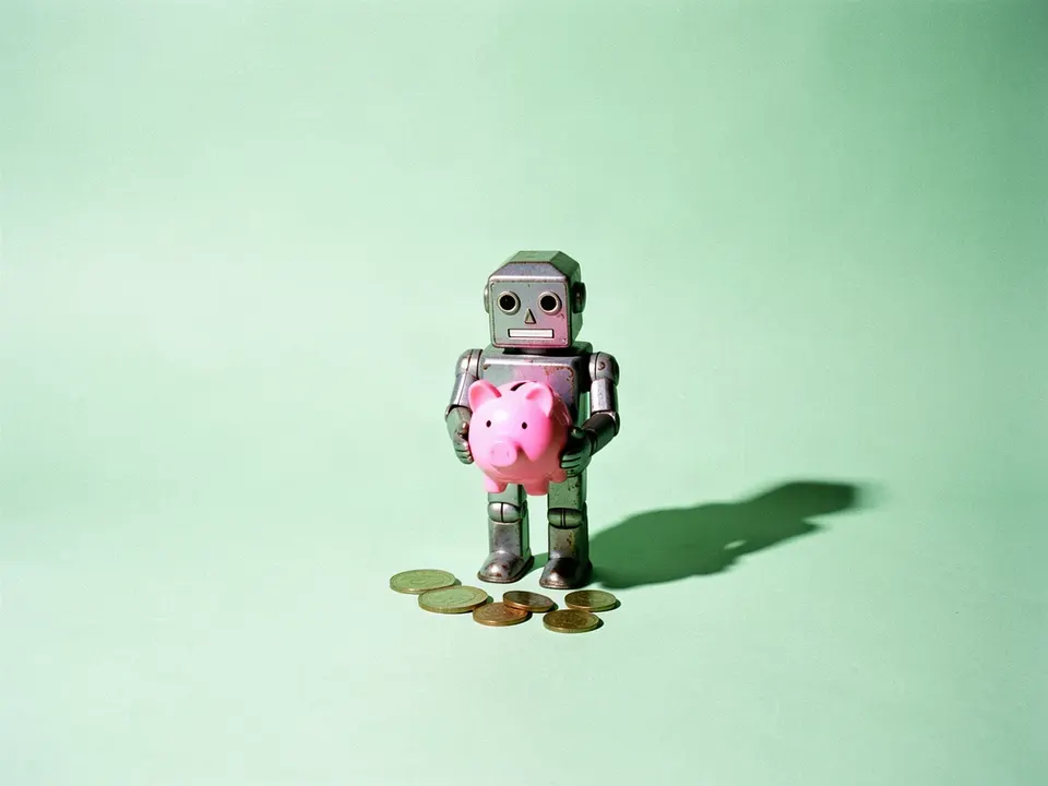 Un robot de juguete de lata con una alcancía de cochinito y monedas