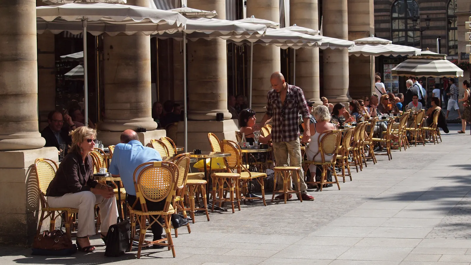 Terraza de café bajo las arcadas de la plaza Colette, en París